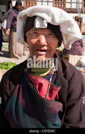 Bhutanischen Seniorin verkaufen sie waren in einem Markt und mit einem weißen Kopfschmuck geschmückt. Stockfoto