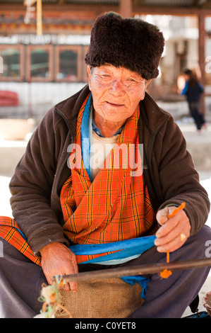 Älterer bhutanischen Mann in eine Pelzmütze, seine waren in der Paro-Marktplatz zum Verkauf Stockfoto