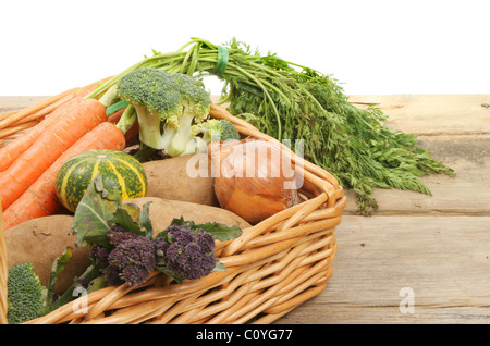 Frisches Gemüse in einem Weidenkorb auf einer Holzbank Stockfoto
