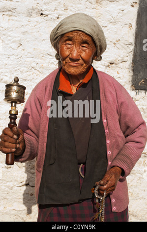 Porträt einer bhutanischen Seniorin mit einer Gebetsmühle und Gebetsketten im Bhumtang, Bhutan. Stockfoto