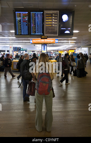 Frau Passagier schaut Abfahrt Display / monitor / Fernseher / tv Fahrplan Display / Bildschirm schwarzen Brett. Heathrow Flughafen Stockfoto