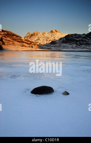 Winter-Morgensonne auf der Langdale Pikes über einen gefrorenen Blea Tarn im englischen Lake District Stockfoto