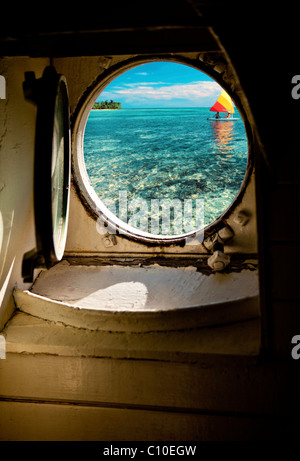 SCHIFFS-BULLAUGE INNEN BLICK AUF OZEAN MIT INSEL UND PAAR AUF SEGELBOOT Stockfoto