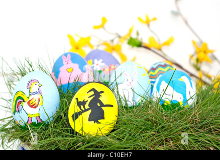 Eine Auswahl von Hand gemalt, dekorative Ostern Eierschalen; mit einer skandinavischen Ostern Hexe im Fokus; grüner Frühling Gras Stockfoto