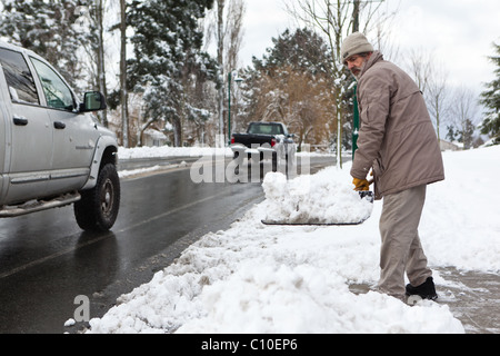 Ein Mann schaufelt Schnee unterwegs Helmcken in View Royal, BC, Kanada. Stockfoto