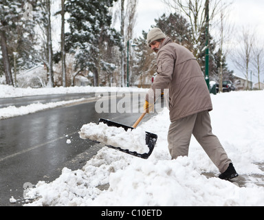 Ein Mann schaufelt Schnee unterwegs Helmcken in View Royal, BC, Kanada. Stockfoto