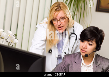 Weiblichen Arzt bespricht Arbeit am Computer mit Empfangsdame Assistentin in einer Büroumgebung. Stockfoto
