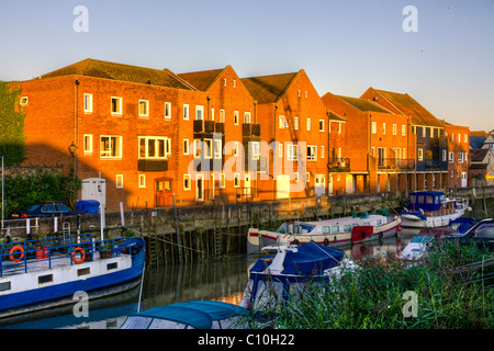 Sanierung Moderne dreistöckige Wohnterrasse am Flussufer in der Stadt Sandwich in Kent. Kahnen und Boote, die im Vordergrund auf dem Fluss festgemacht wurden. Stockfoto