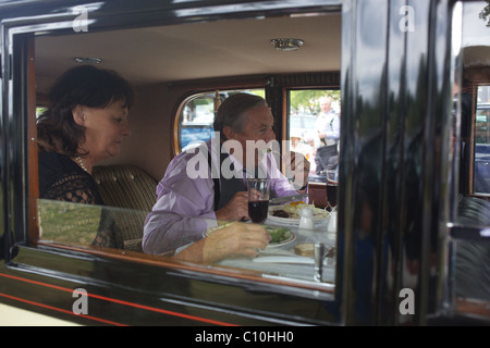 Ein paar genießen Sie Mittagessen in einem Oldtimer Parken in einem Parkhaus in der Royal Ascot-Rennen-Sitzung. Stockfoto