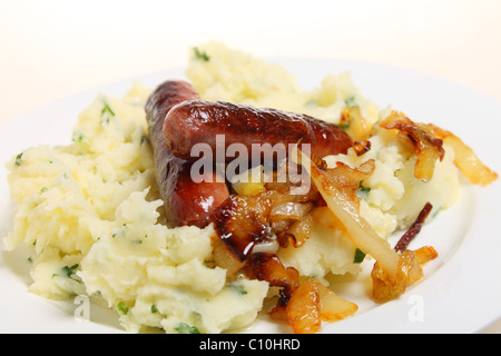 Traditionelle britische "Bangers and Mash" essen Würstchen mit Kartoffelbrei Petersilienkartoffeln und karamellisierten Zwiebeln auf einem Teller. Stockfoto