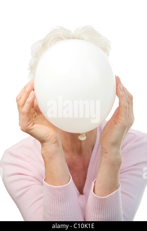 Eine reife Frau, die einen weißen Ballon vor ihr Gesicht halten Stockfoto