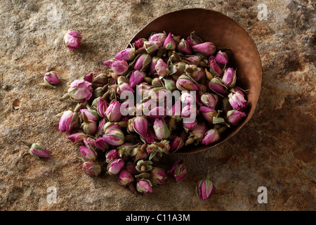 Rosenknospen (Rosa) in einer kupfernen Schüssel auf eine Steinoberfläche Stockfoto