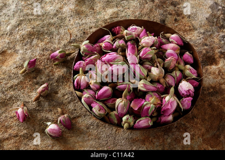 Rosenknospen (Rosa) in einer kupfernen Schüssel auf eine Steinoberfläche Stockfoto