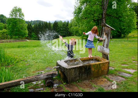 Kinder spielen mit Wasser bei der Fontäne Stockfoto
