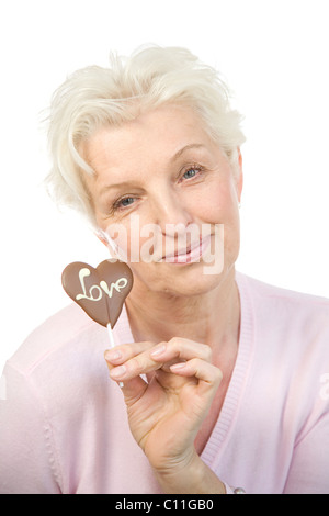 Eine reife Frau mit einem Schokoladen Herz mit dem Wort "Liebe" in der hand Stockfoto