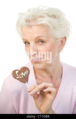 Eine reife Frau mit einem Schokoladen Herz mit dem Wort "Liebe" in der hand Stockfoto