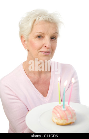 Eine reife Frau einen Teller mit einem Donut mit Kerzen in ihren Händen hält Stockfoto