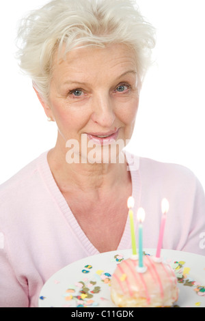 Eine reife Frau einen Teller mit einem Donut mit Kerzen in ihren Händen hält Stockfoto