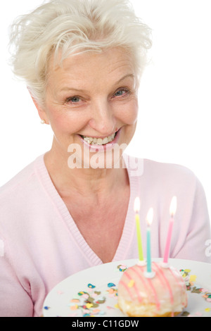 Eine reife Frau einen Teller mit einem Donut mit Kerzen in ihren Händen hält Stockfoto