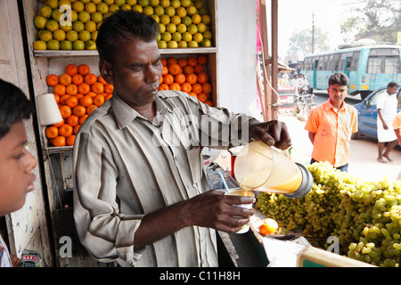 Obst Verkäufer Gießen frisch gepressten Orangensaft in Tasse, Punjaipuliampatti, Tamil Nadu, Tamil Nadu, Südindien, Indien, Südasien, Asien Stockfoto