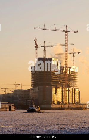 Ein Schlepper Boot auf der winterlichen Elbe im Hamburger Hafen, im Hintergrund die Baustelle der Elbphilharmonie Philharmonie Stockfoto