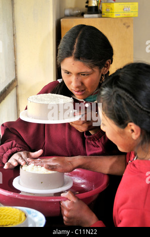 Herstellung von Frischkäse im Tal Penas, zwei junge Mädchen quetschen Käse in runder Form, Departamento Oruro, Bolivien Stockfoto