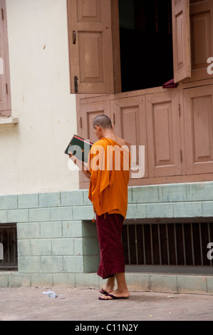 Myanmar (aka Burma), Mandalay, Amarapura. Mahagandayone Kloster, das größte Kloster in Myanmar. Mönch zu lesen. Stockfoto