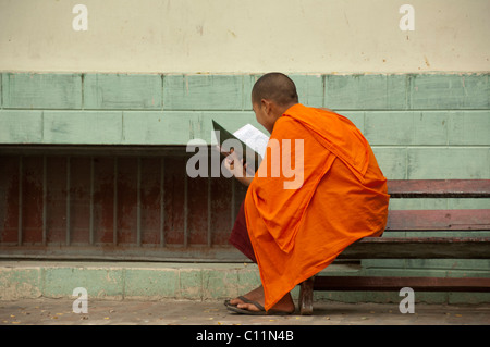 Myanmar (aka Burma), Mandalay, Amarapura. Mahagandayone Kloster, das größte Kloster in Myanmar. Mönch zu lesen. Stockfoto