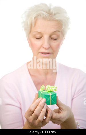 Alte Frau mit Blick auf die Gegenwart in ihren Händen dazulernen Stockfoto