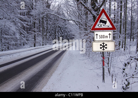 Warnzeichen im Winter, Verkehrsschilder Warnung vor Rutschgefahr auf Glatteis und Schnee auf eisglatten Straße in den Wald Stockfoto