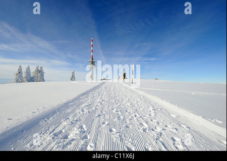 Gewalzten Schnee trail auf dem 1493m hohen Mt. Feldberg im Schwarzwald, am Horizont die neue Feldbergturm-Antenne mit der Stockfoto