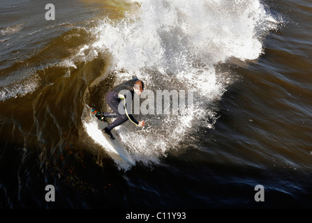 Surfer aufsteht auf einer Welle. Die Welle dreht sich mit Schaum und Spritzer. Stockfoto