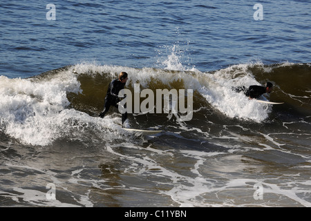 Surfer auf einer Welle aufsteht. Die Welle dreht sich mit Schaum und Spritzer. Stockfoto