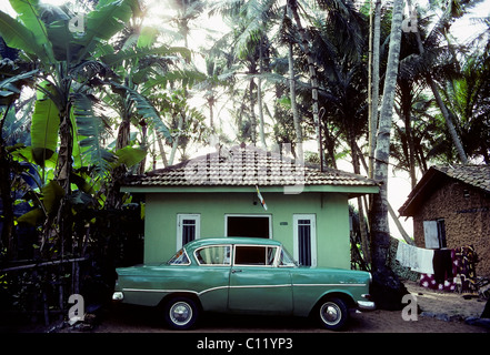 Grüne Oldtimer geparkt vor einem kleinen, grünen gemalte Haus unter Palmen, Opel Rekord, Sri Lanka, Ceylon, Südasien, Asien Stockfoto