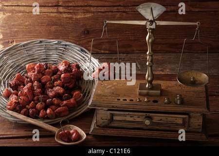 Antike Waage mit einem Gewicht von getrockneten Mini Paprika (Capsicum) auf eine Holzoberfläche Stockfoto