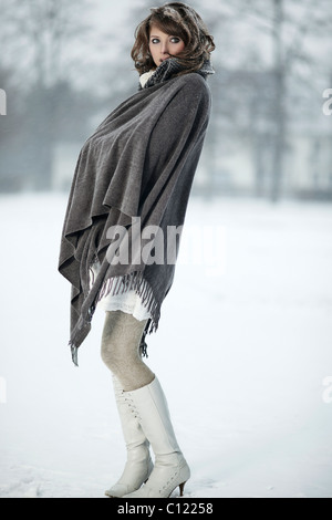 Junge Frau im Schnee, verpackt in einem poncho Stockfoto