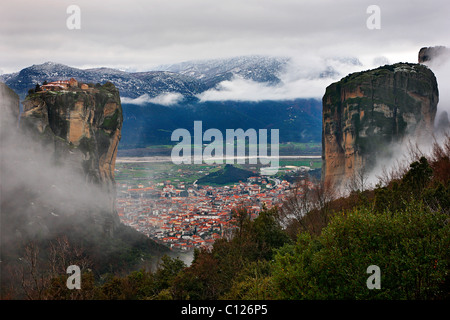 Kalambaka Stadt gesehen "durch" die Felsen von Meteora. Oben auf dem linken Felsen ist das Kloster Aghia Triada ("Heilige Dreifaltigkeit"). Stockfoto