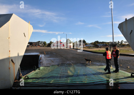 Zwei Arbeiter, rote Jacken, stehend auf der offenen Rampe einer Fahrzeug-Fähre vertäut am Kanal von Chacao Terminal, Pargua, Chile Stockfoto