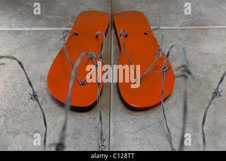 Orange Stacheldraht Flip-flops hinter Stacheldraht. Stockfoto