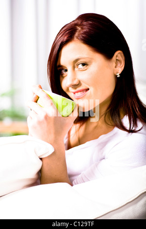 Junge Frau mit Tasse Tee im Wohnzimmer Stockfoto