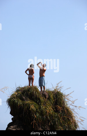 Ein Mann nimmt ein Bild von einer Frau aus auf einer Felsformation am Strand an der Manuel Antonio National Park in Costa Rica Stockfoto