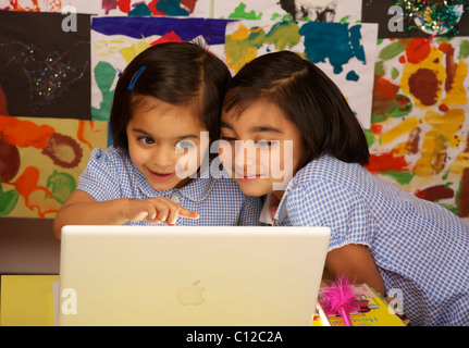 2 junge Mädchen auf der Suche an einem Laptop Computer uk Stockfoto