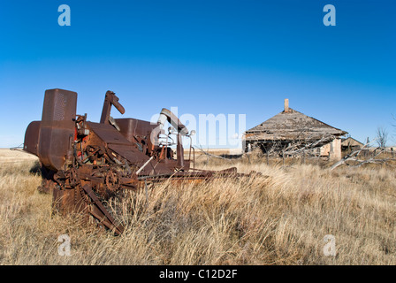 Rostige alte Landmaschinen sitzt vor einem verlassenen Haus in Quay County, New Mexico. Stockfoto