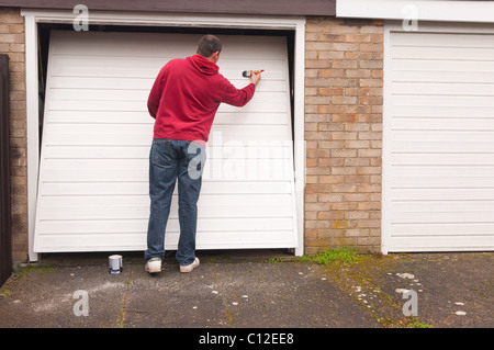 Ein MODEL Release Mann tun DIY Malerei ein Garagentor im Vereinigten Königreich Stockfoto