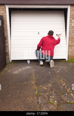 Ein MODEL Release Mann tun DIY Malerei ein Garagentor im Vereinigten Königreich Stockfoto
