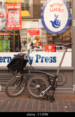 Ein Brompton Fold away Fahrrad zusammengefaltet außerhalb Uk-shop Stockfoto