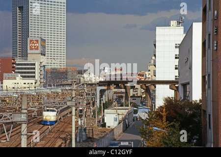 Shinkansen-Hochgeschwindigkeitszug kurz vor dem Bahnhof Tokio mit einem lokalen Monorail-Zug auf der Brücke über c.1982 Stockfoto