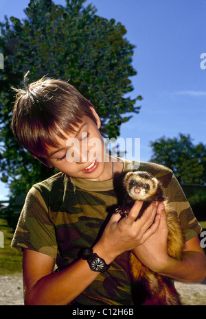 Junge, Alter 8-10 Jahre alt mit Haustier Frettchen im Sommer Stockfoto