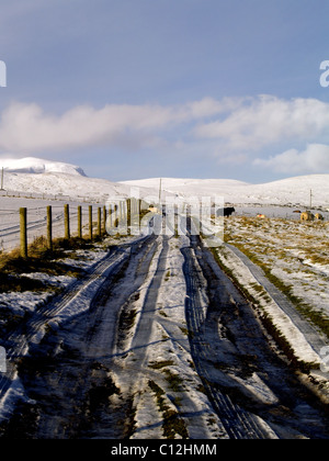 Nachschlagen von einer verschneiten Straße auf einem Bergbauernhof in den schottischen Highlands im Winter. Stockfoto