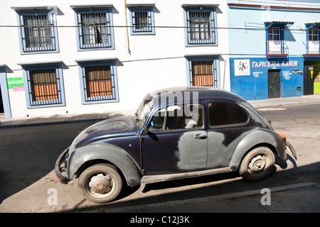 ehrwürdige Volkswagen Käfer Bug mit gepatchten Körperarbeit parkte am Bordstein des typischen bunten Oaxaca Straße-Mexiko Stockfoto